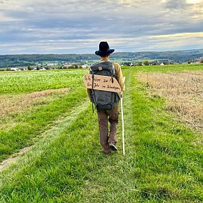 Ein Wanderer von hinten mit einem Schild auf dem Rücken mit der Aufschrift Ich höre zu Copyright Daniel Beerstecher